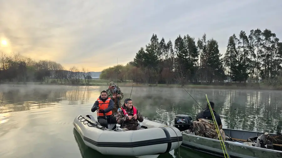 Botes inflables sobre el agua al amanecer, con niebla y el sol asomando entre los árboles