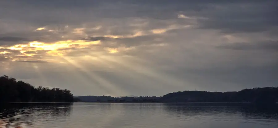Rayos de sol atravesando las nubes sobre la laguna al atardecer