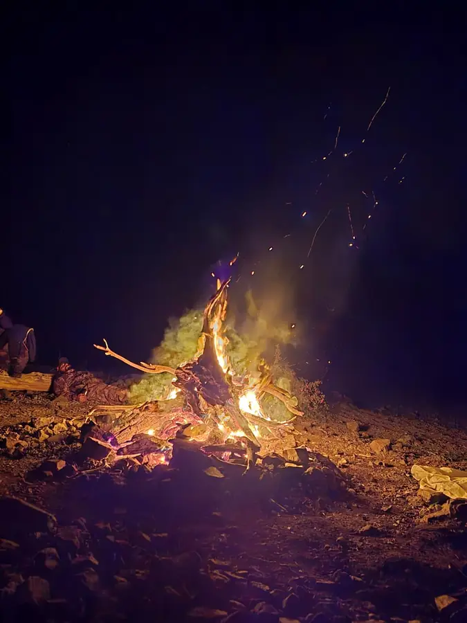 Fogata encendida de noche al borde del lago