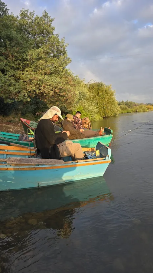 Dos botes de madera amarrados a la orilla con socios preparando los aparejos al amanecer
